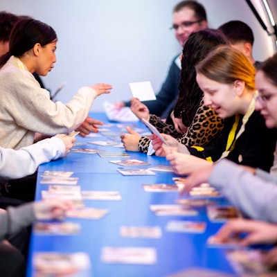 Das Bild zeigt einige Schülerinnen und Schüler, die sich Bilder auf kleinen Karten anschauen.