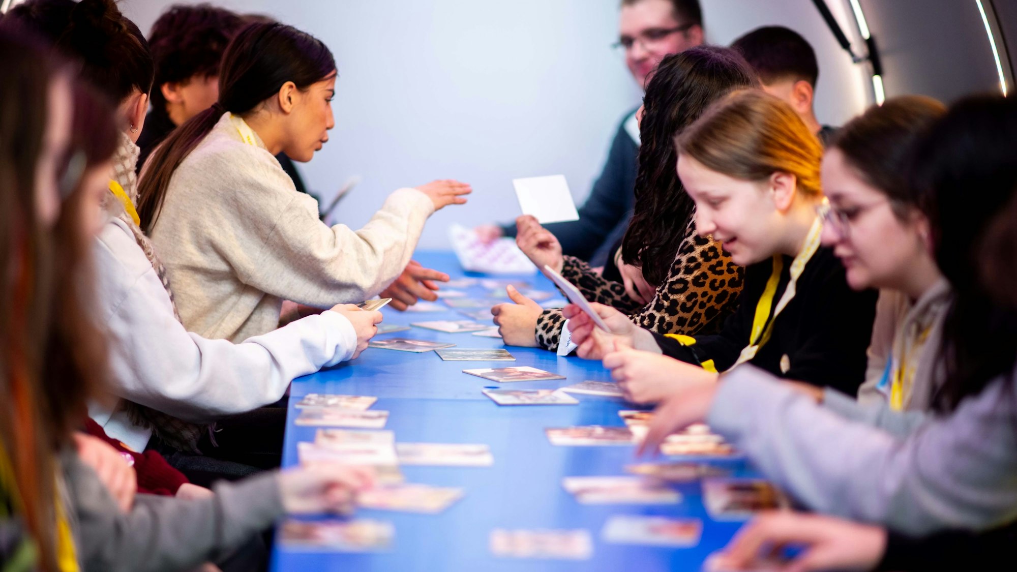 Das Bild zeigt einige Schülerinnen und Schüler, die sich Bilder auf kleinen Karten anschauen.