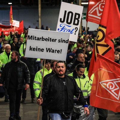 Köln: Ein Mitarbeiter hält auf dem Weg zur Betriebsversammlung ein Plakat mit der Aufschrift ·Mitarbeiter sind keine Ware· in der Hand.
