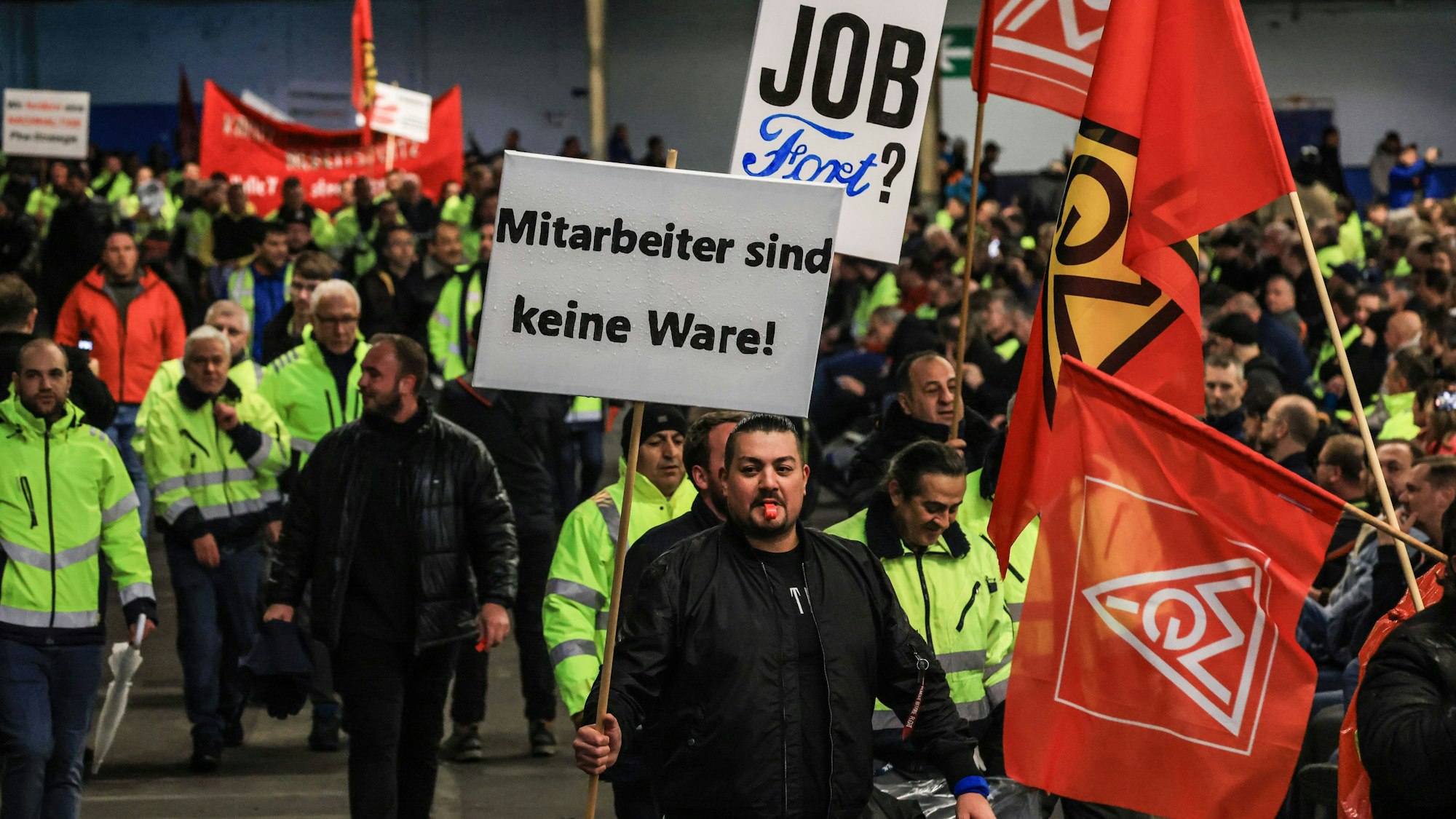 Köln: Ein Mitarbeiter hält auf dem Weg zur Betriebsversammlung ein Plakat mit der Aufschrift ·Mitarbeiter sind keine Ware· in der Hand.