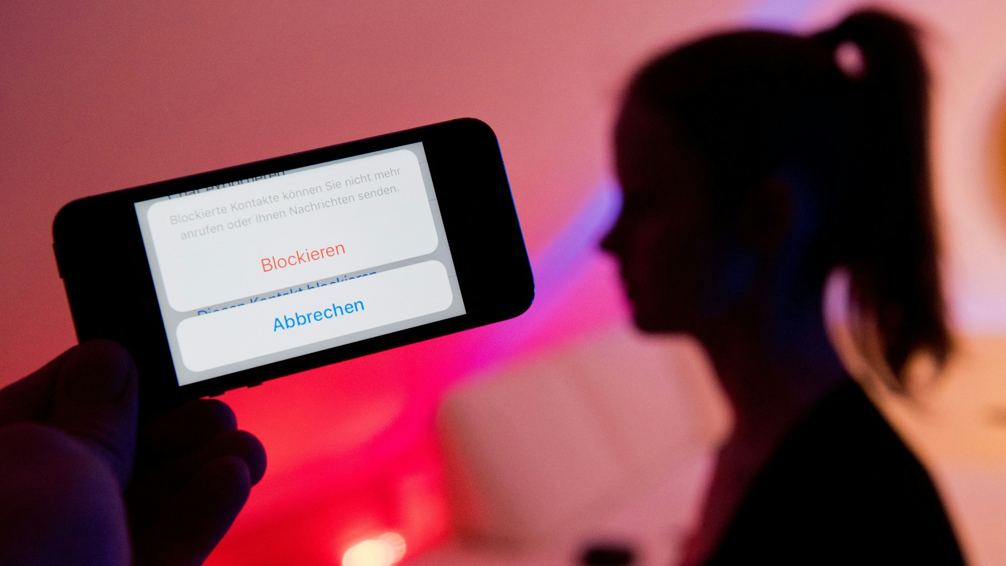 Ein junges Mädchen zeigt am 04.02.2017 das Display eines Smartphones mit einem Button „Blockieren“ beim Messenger WhatsApp (gestellte Szene).