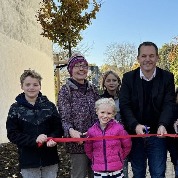 Drei Kinder, eine Frau und ein Mann schauen in die Kamera, sie lächeln.