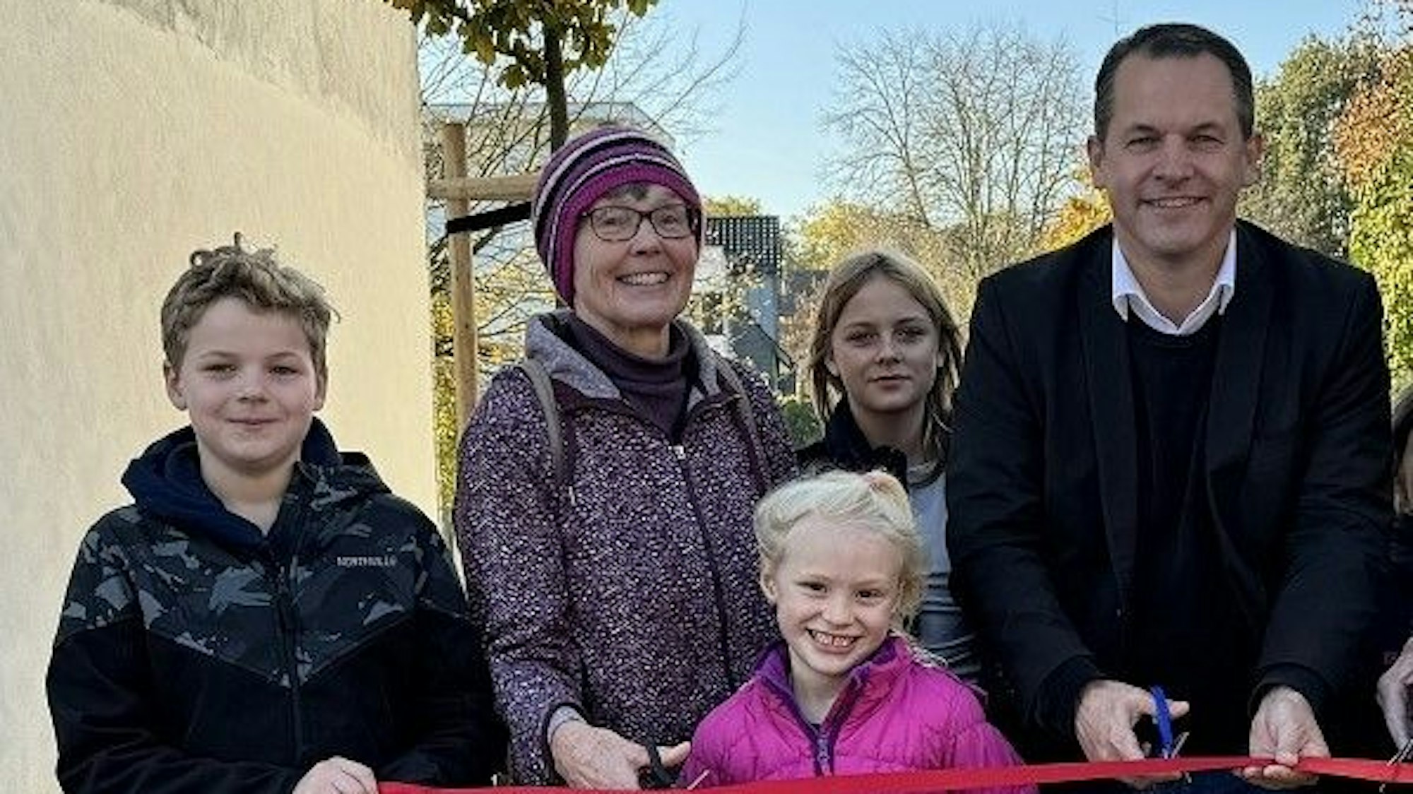 Drei Kinder, eine Frau und ein Mann schauen in die Kamera, sie lächeln.