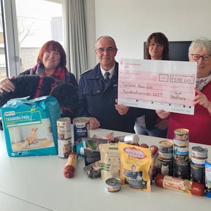 Vor den genannten Personen liegen Dosen, Tüten und Säcke mit Tierfutter auf einem Tisch.
