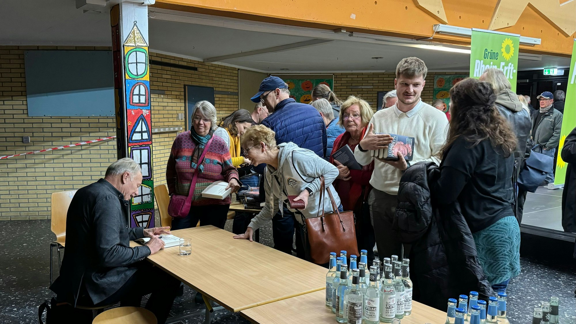 Auf dem Bild sind Menschen zu sehen, die sich Bücher signieren lassen.
