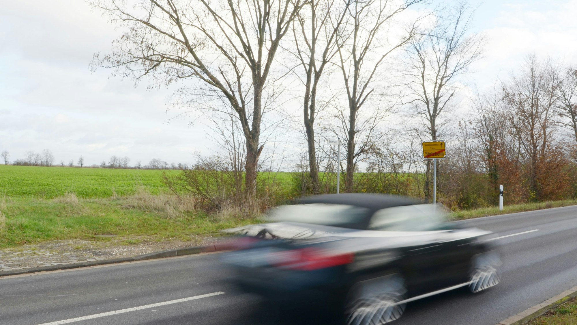 Blick auf eine Fläche am Ortsrand von Stotzheim. Über die Selmenstraße fährt ein Auto.