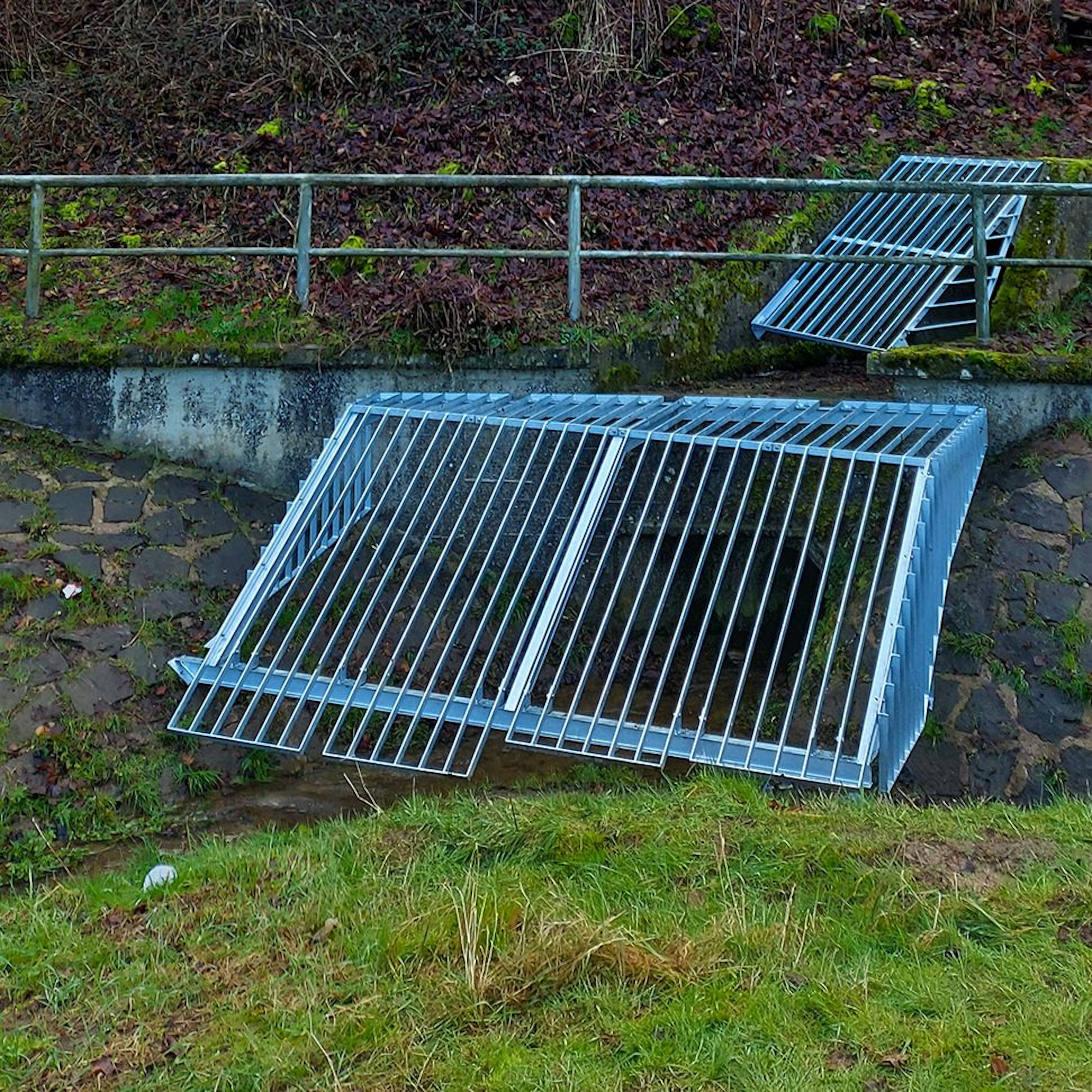 Ein großes Gitter ist an einem Bachlauf angebracht.