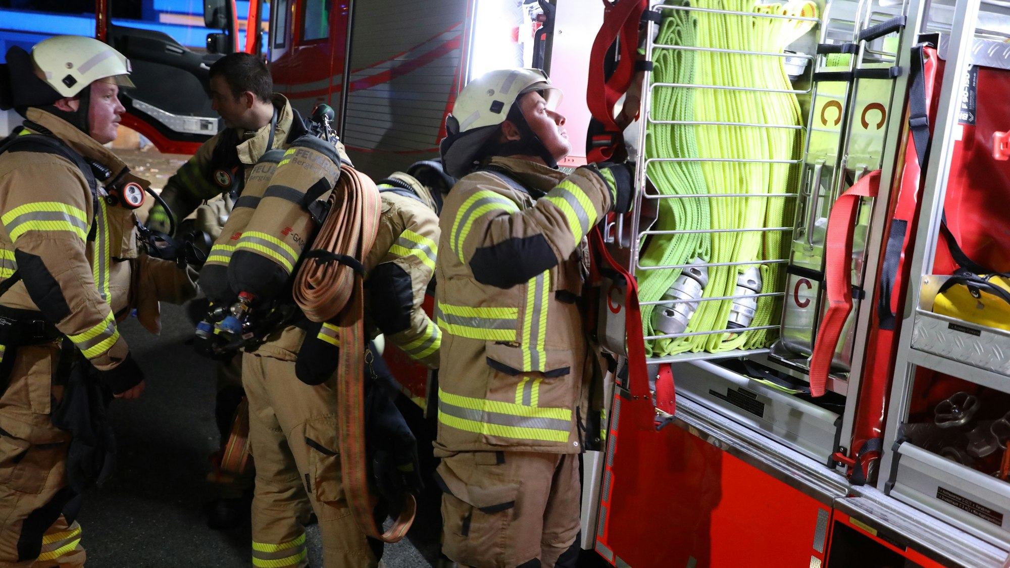 Feuerwehrleute holen sich Schläuche und Masken aus dem Feuerwehrwagen.