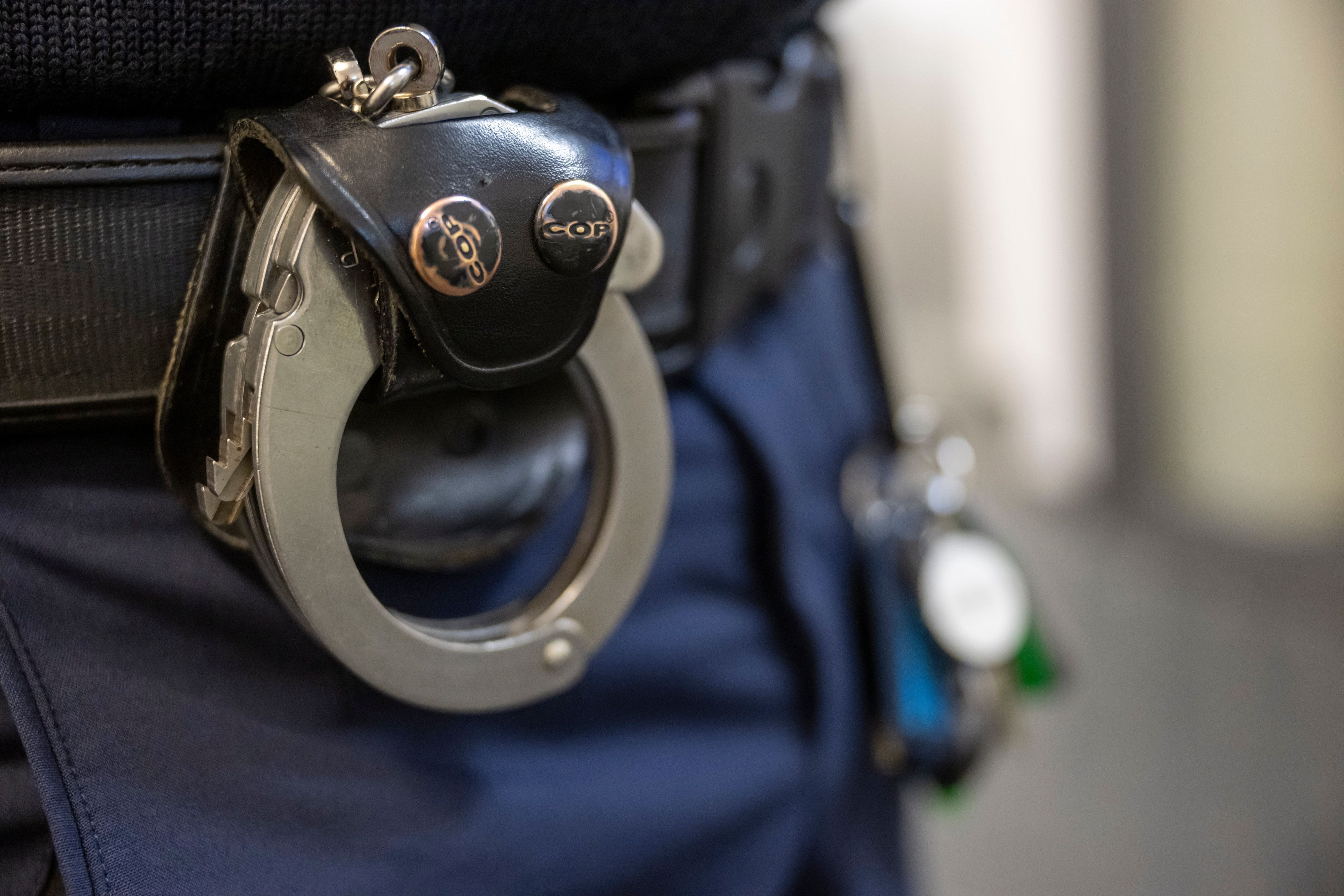 Eine Handschelle hängt am Gürtel eines Polizisten der Polizeiinspektion 11.