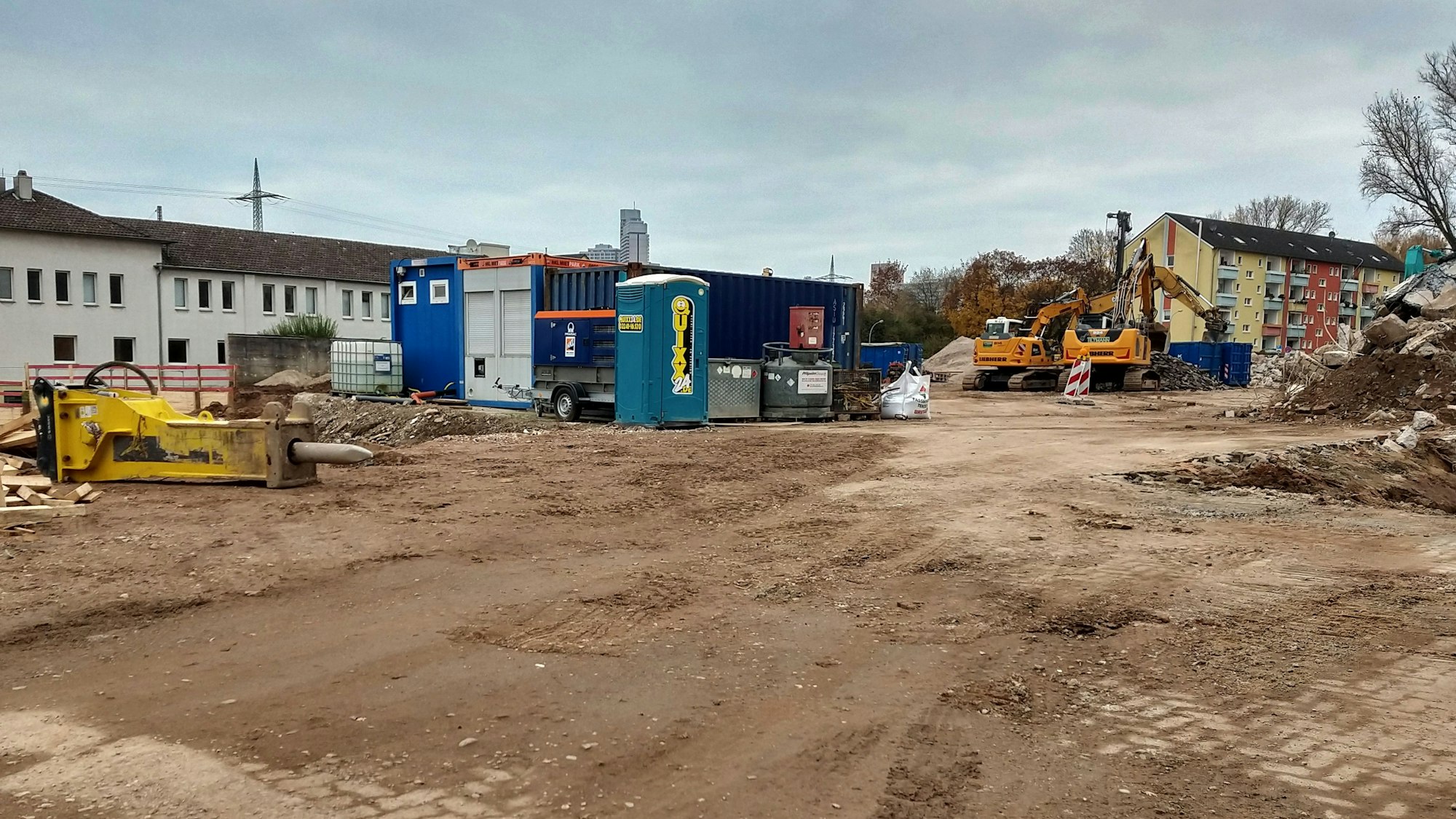 Blick auf ein freies Baugrundstück mit Dixi-Klo und einem Bagger