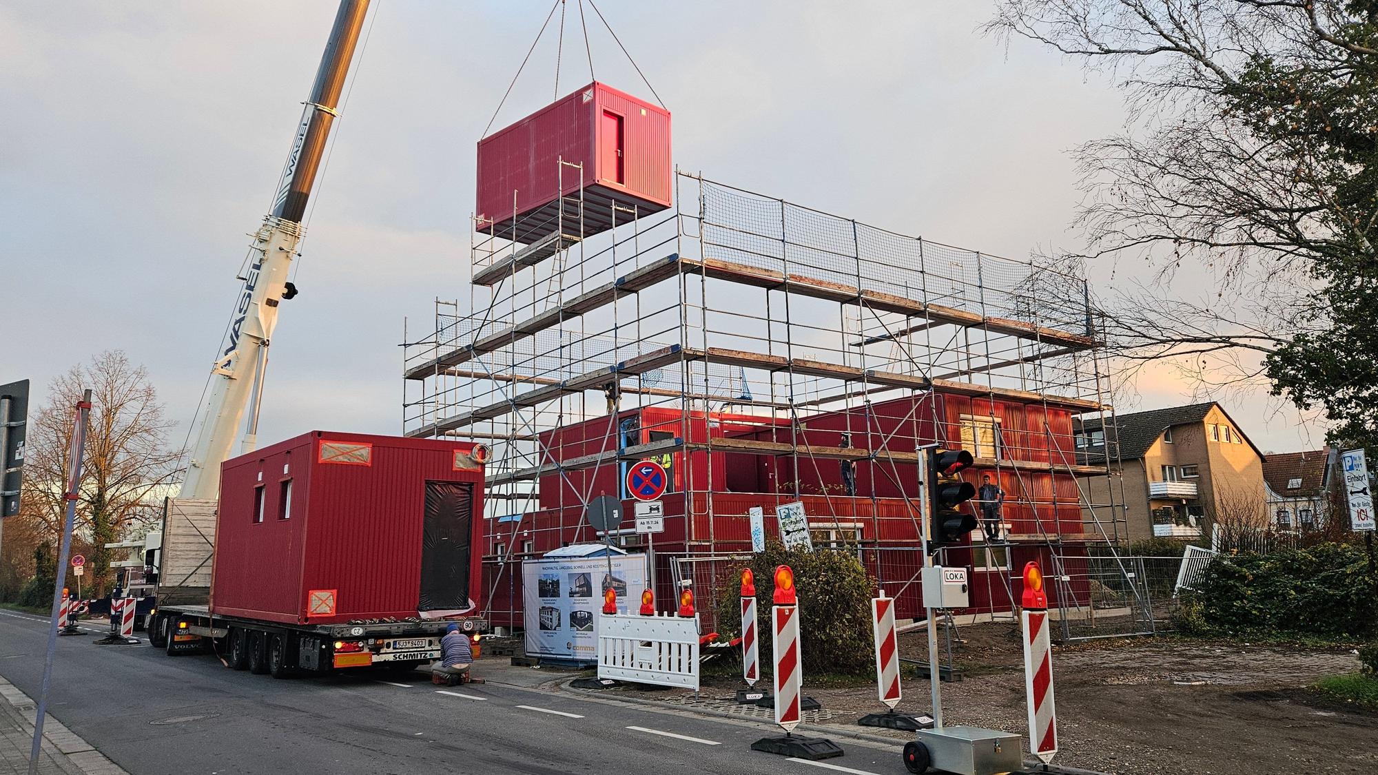 Ein Mobilkran hievt Container aufeinander, eine Unterkunft für Geflüchtete entsteht.