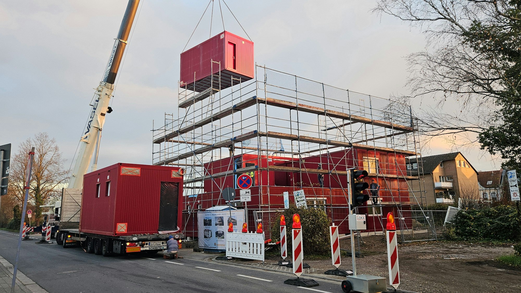 Ein Mobilkran hievt Container aufeinander, eine Unterkunft für Geflüchtete entsteht.