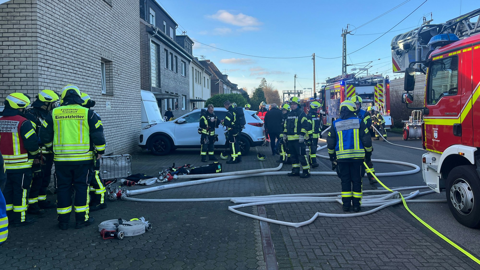 Zahlreiche Feuerwehrleute und Einsatzfahrzeuge stehen vor einem Haus in Spich.