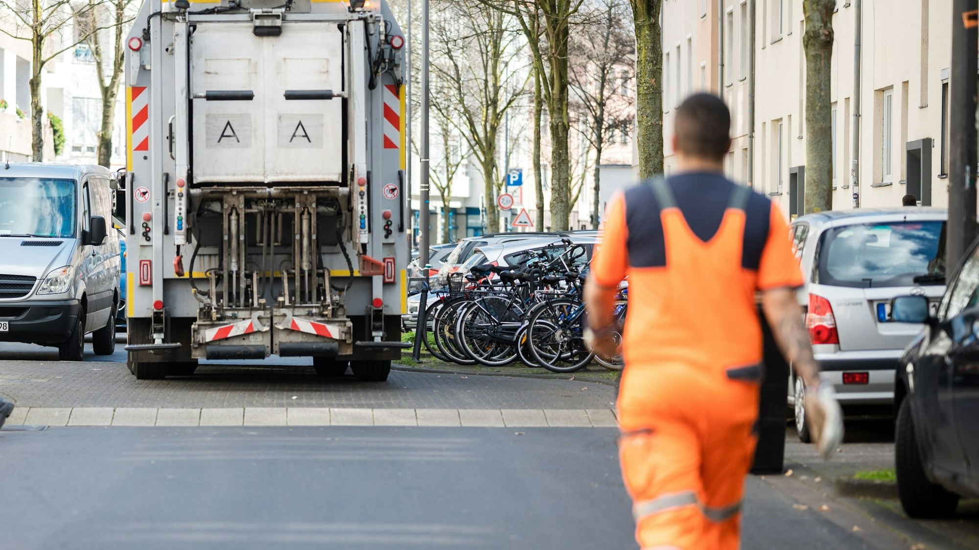 Ein Müllauto der AWB steht in einer Straße, ein Mitarbeiter der AWB läuft dem Auto hinterher.