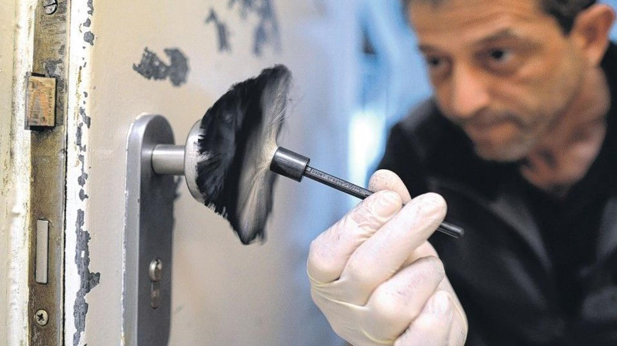 Ein kriminaltechnischer Angestellter der Polizei sichert Spuren an einer Eingangstür.