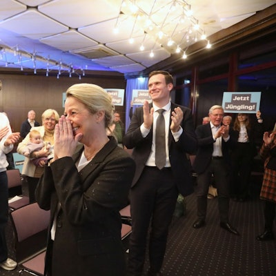 Mehrere Menschen applaudieren einer Frau, teilweise halten sie Schilder mit der Aufschrift „Jetzt Jüngling“ in die Höhe.