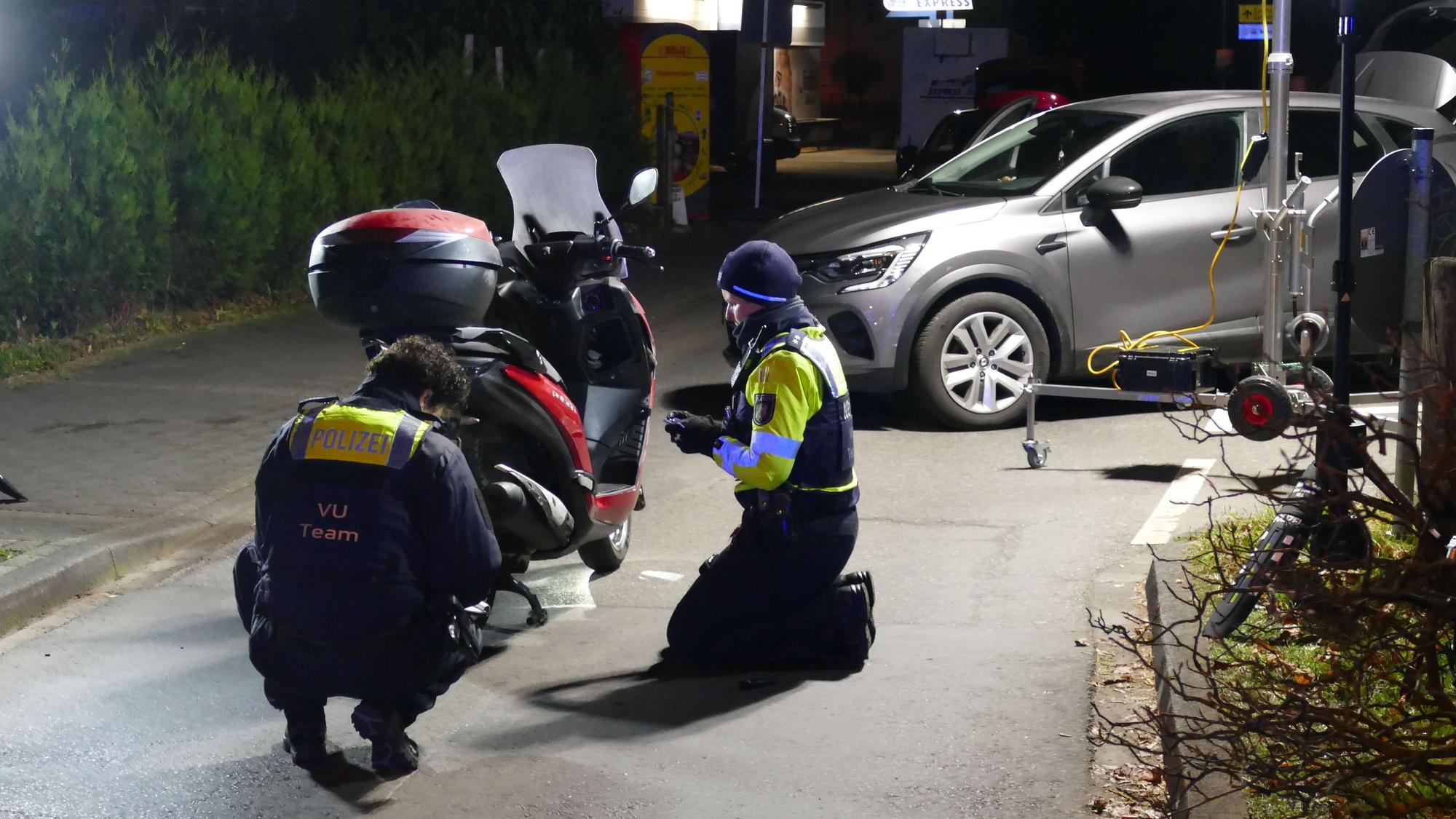 Polizeibeamte untersuchen den Motorroller.