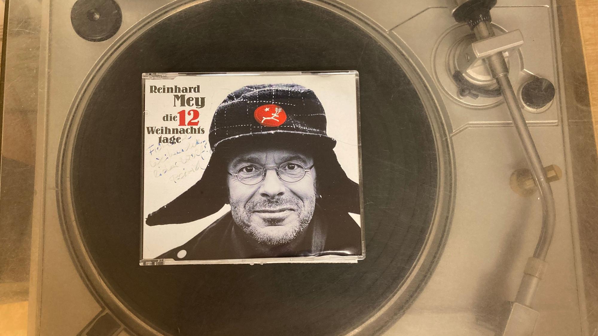 Eine CD zeigt das Gesicht von Reinhard Mey. Der Tonträger liegt auf einem Plattenspieler.