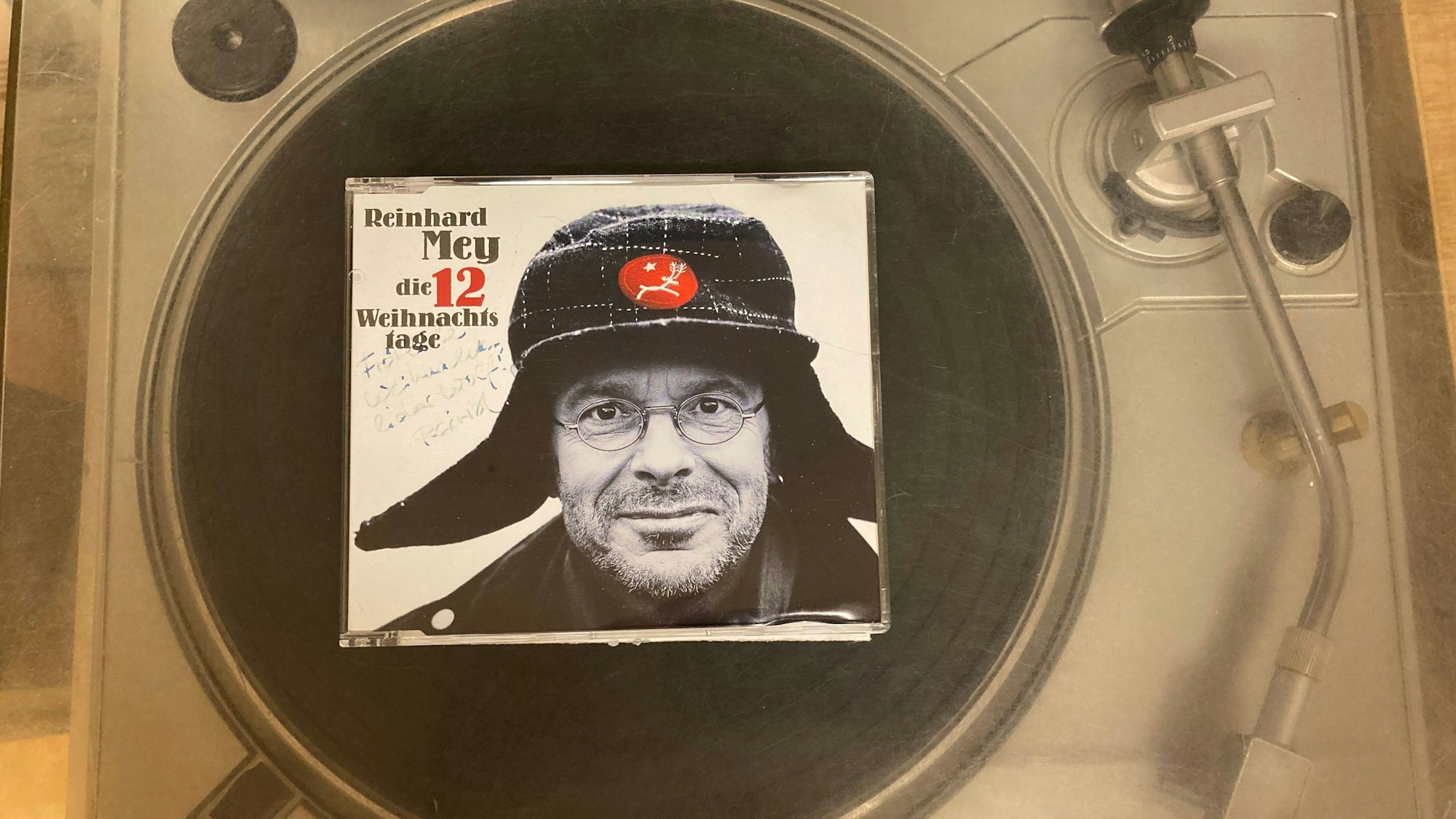 Eine CD zeigt das Gesicht von Reinhard Mey. Der Tonträger liegt auf einem Plattenspieler.