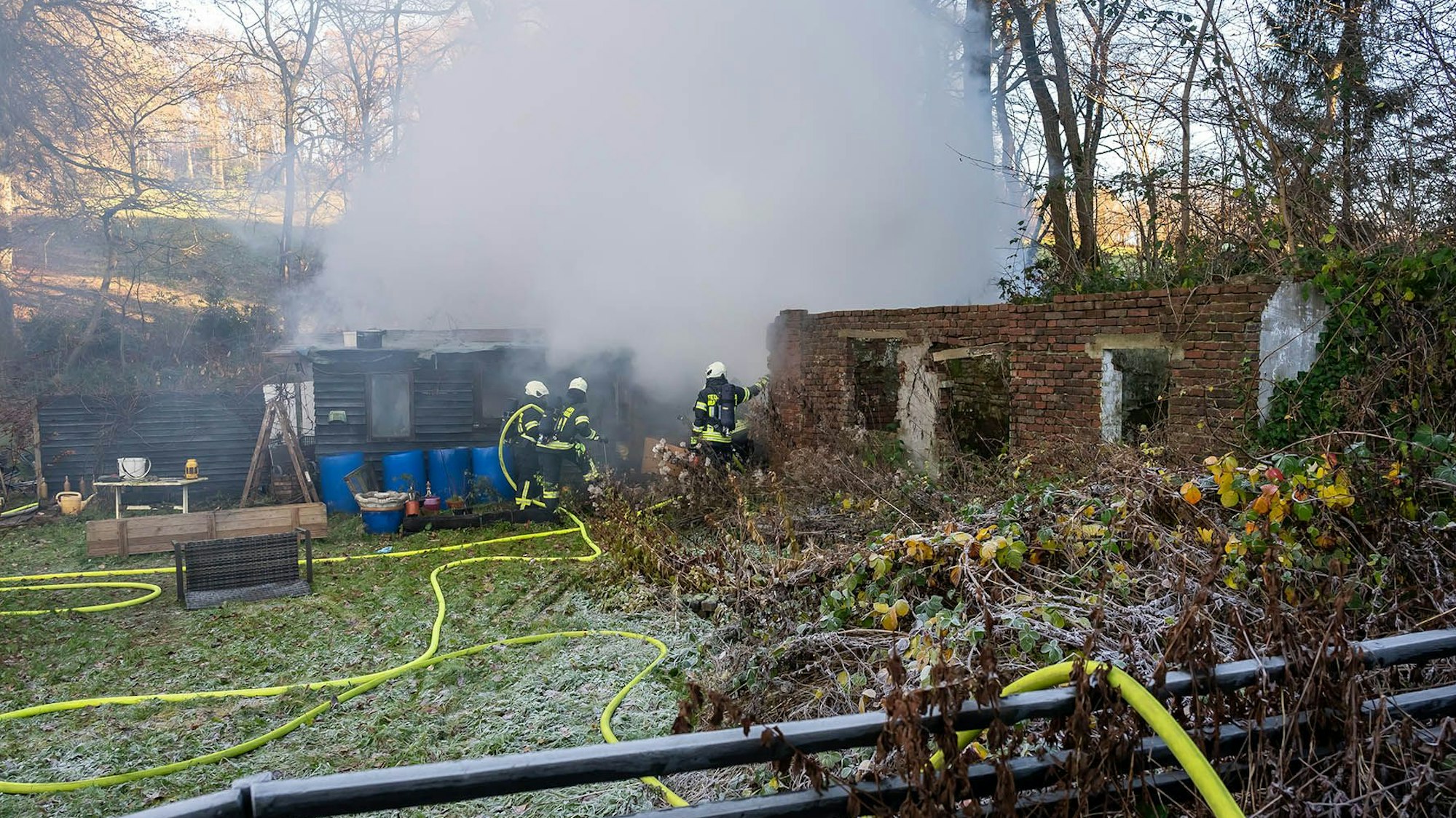 Feuerwehrleute löschen eine brennedne Hütte.