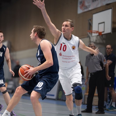 Alex Schöpfer hat den Ball, zwei Gegenspieler bedrängen ihn.