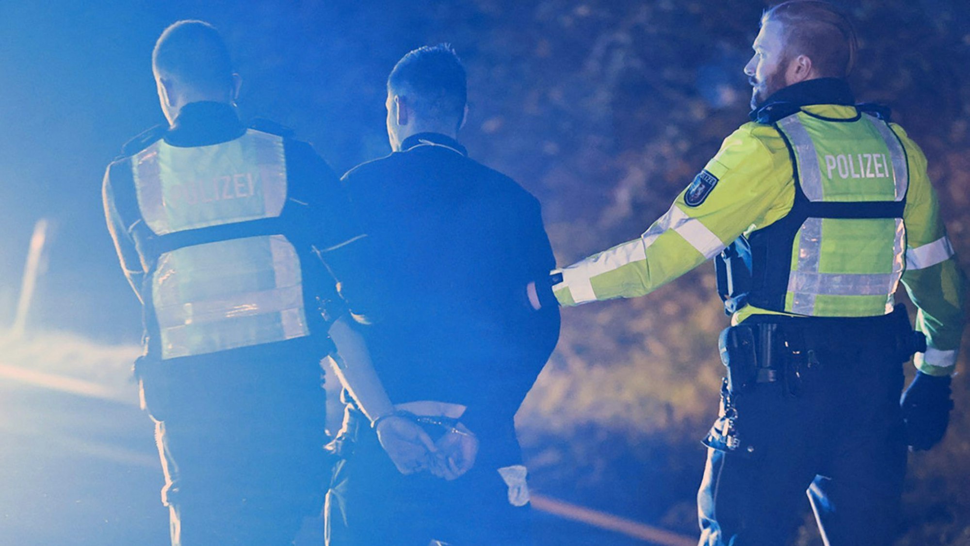 30.11.2024, Nordrhein-Westfalen, Hagen: Polizisten nehmen einen Lastwagenfahrer (M) auf der Autobahn 1 bei Hagen in Gewahrsam. Bei der Chaosfahrt eines Lastwagens über mehrere Autobahnen in Nordrhein-Westfalen sind mehrere Menschen schwer verletzt worden, wie die Polizei mitteilte. Foto: Alex Talash/dpa +++ dpa-Bildfunk +++