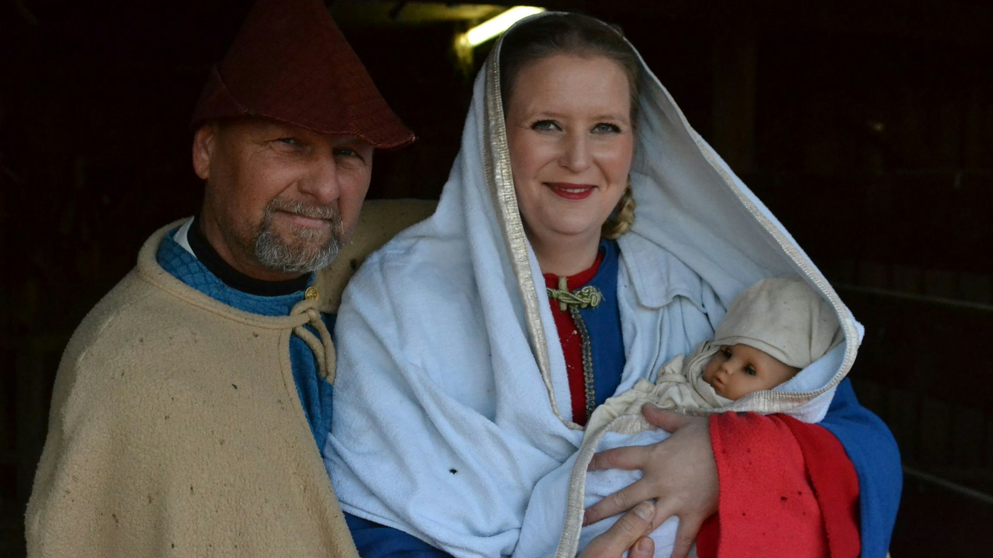 Das Bild zeigt Josef, Maria und Jesus. Während die Eltern von echten Menschen gespielt werden, ist das Christuskind eine Puppe.