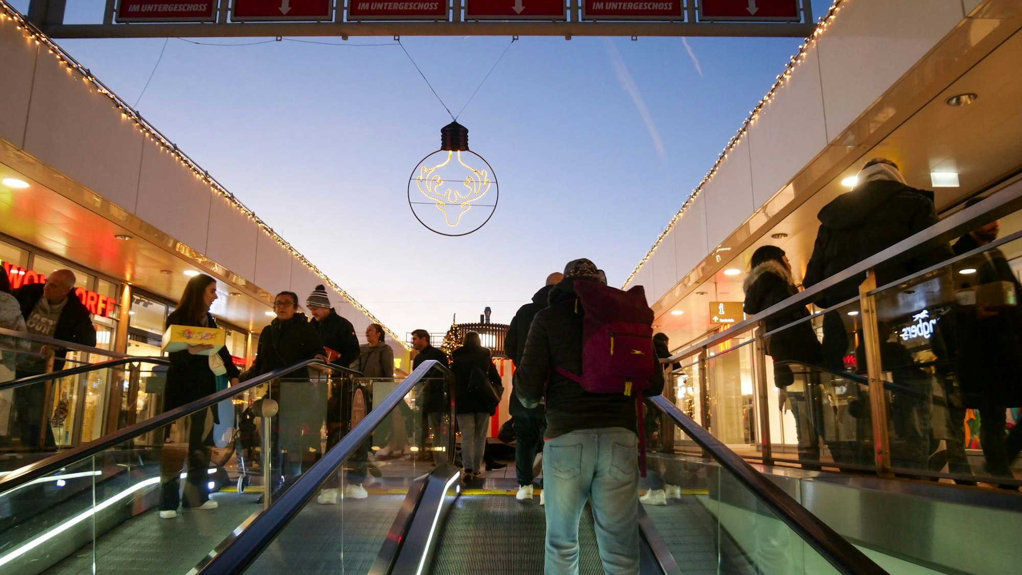 Das Foto zeigt Menschen auf einer Rolltreppe.