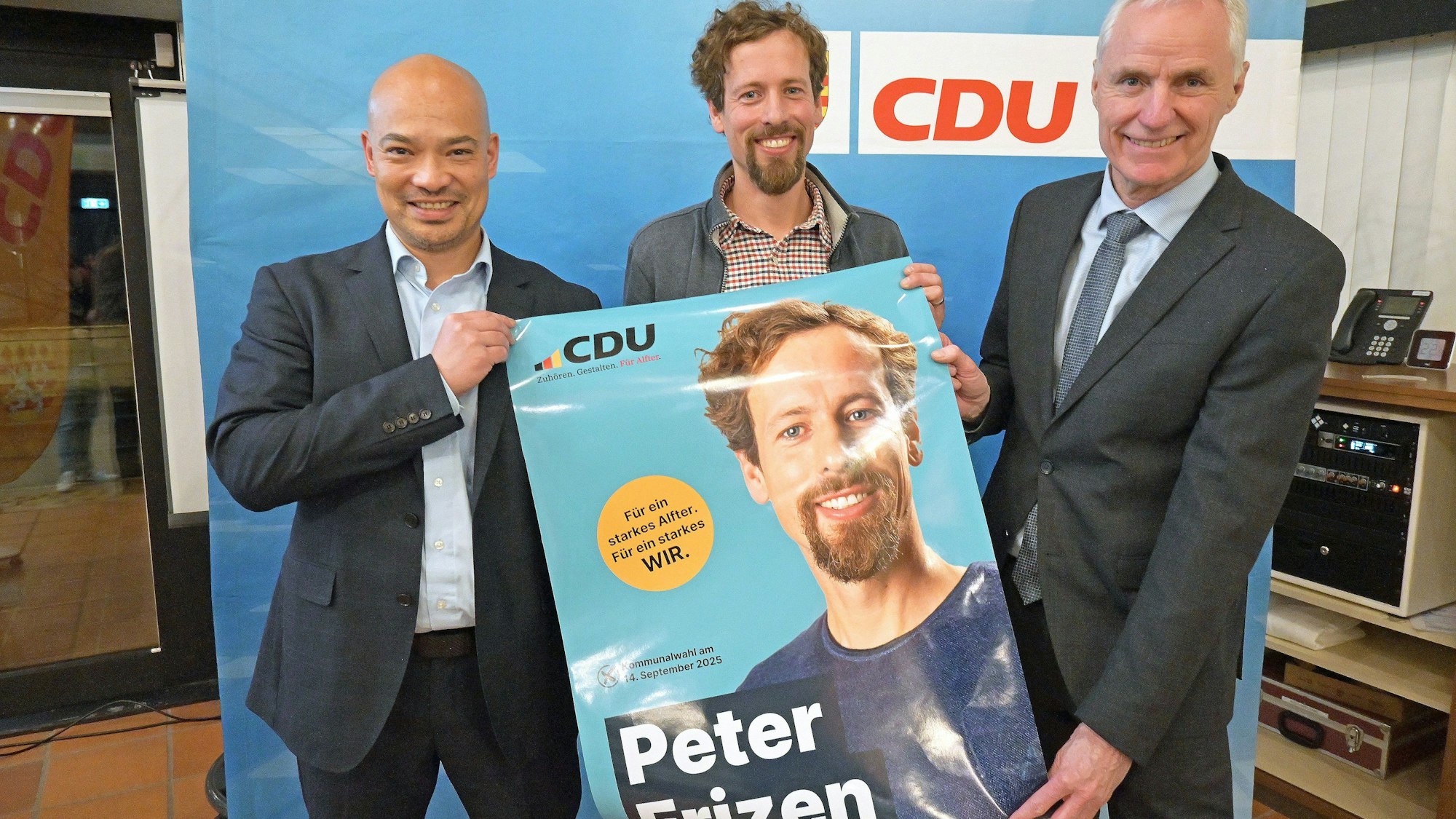 Peter Frizen (Mitte) an der Seite von Christopher Ehlert (links) und Bürgermeister Rolf Schumacher mit seinem Wahlplakat.