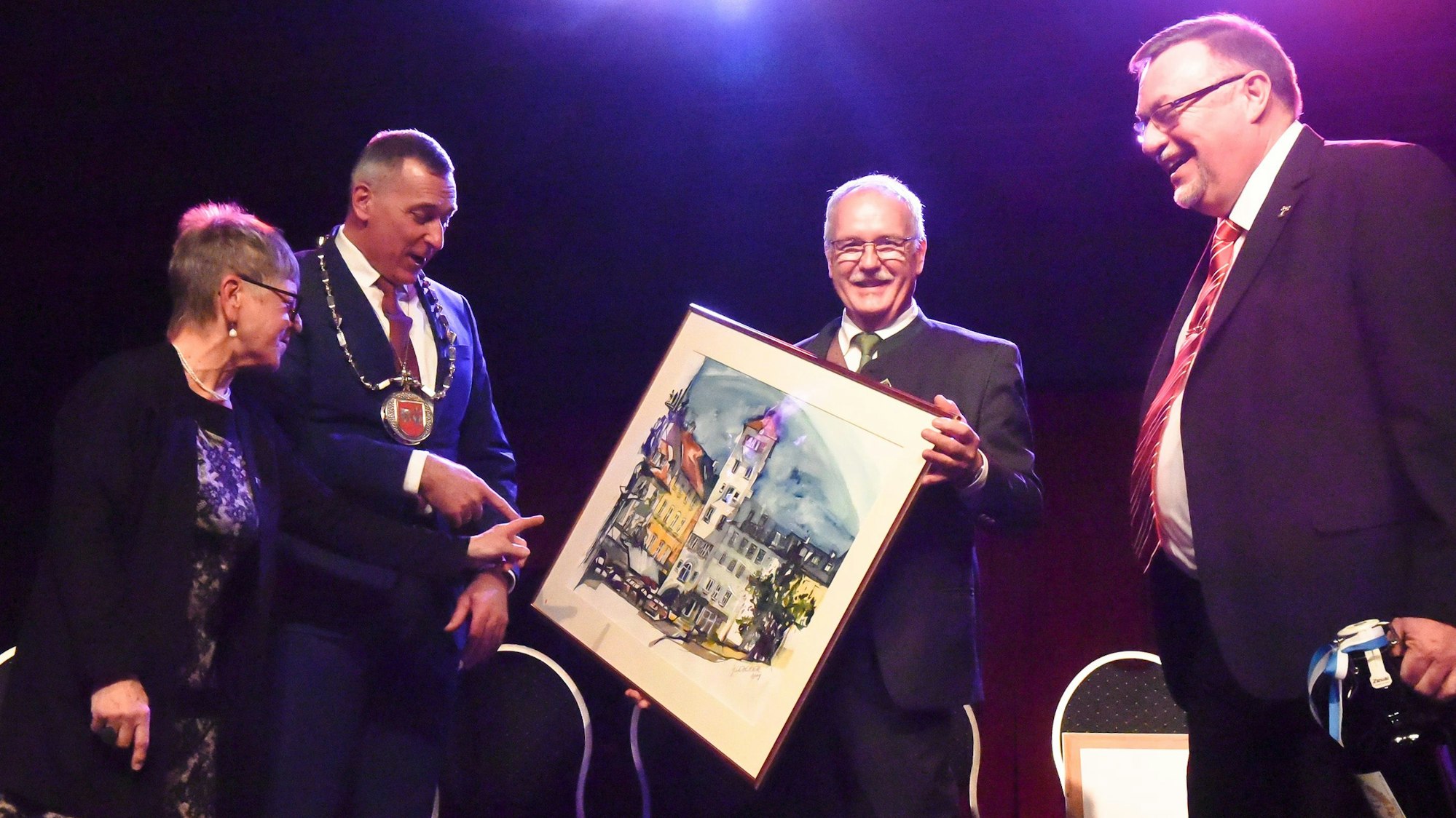 Zu sehen sind eine Frau und drei Männer mit einem Aquarellbild.