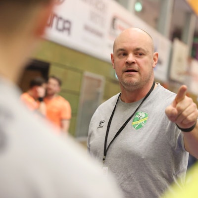 Szene einer Auszeit beim Handball, in der der Trainer etwas erklärt.