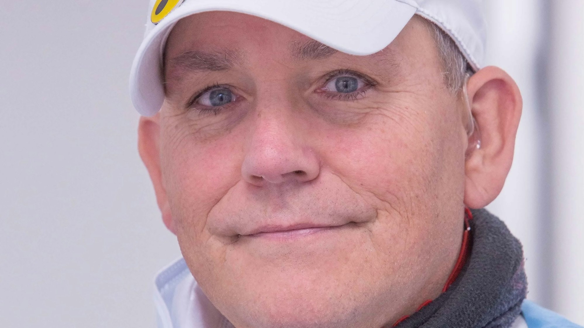 Torsten Polte im Porträt. Er trägt eine weiße Kappe auf dem Kopf, auf der ein gelbes Blindensymbol mit drei schwarzen Punkten befestigt ist.