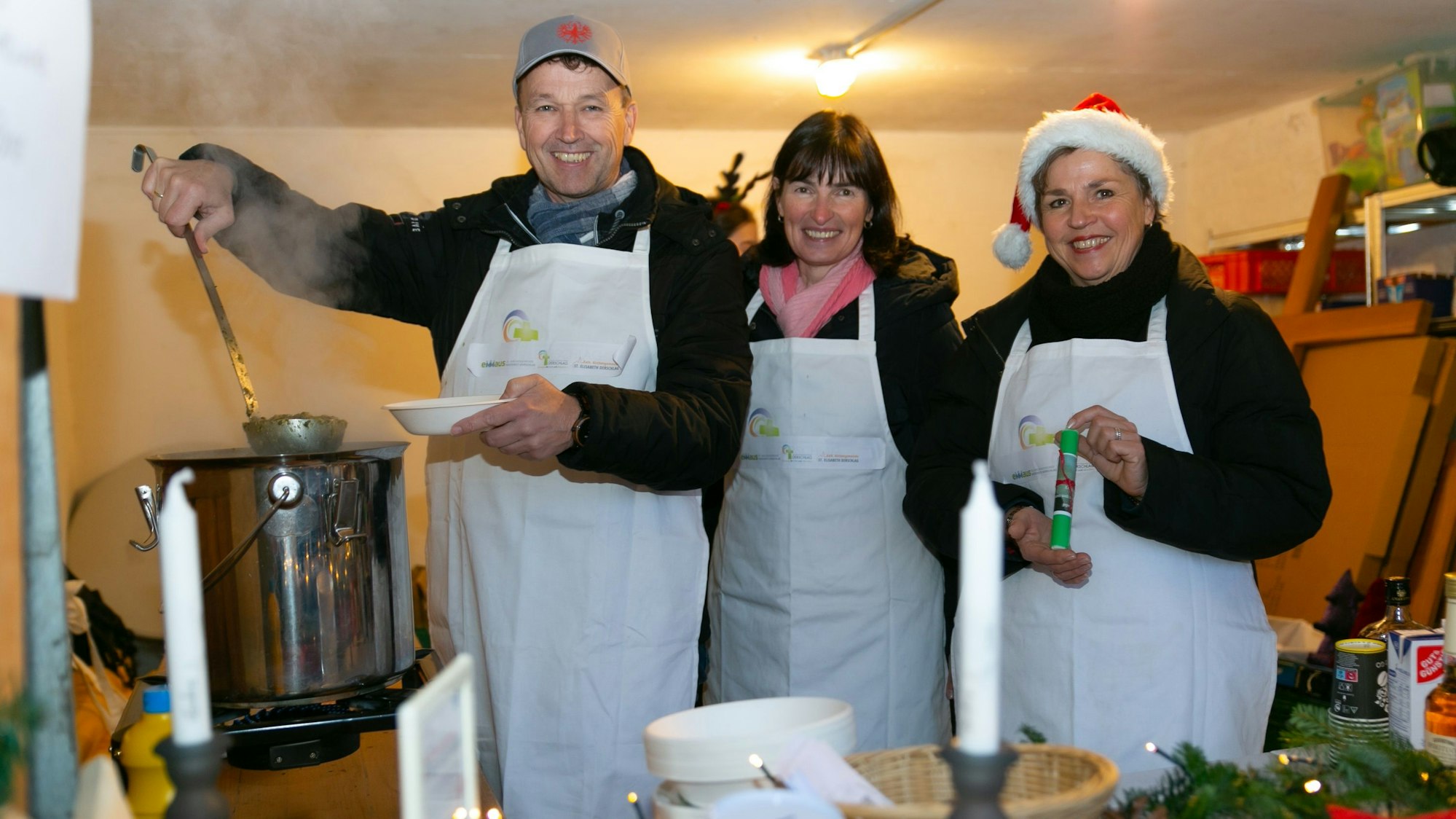 Ein Mann und zwei Frauen stehen an einem großen Topf.