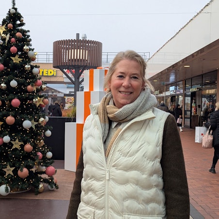 Das Foto zeigt die Center-Managerin neben einem großen Weihnachtsbaum in einer Einkaufspassage im Hürth-Park.