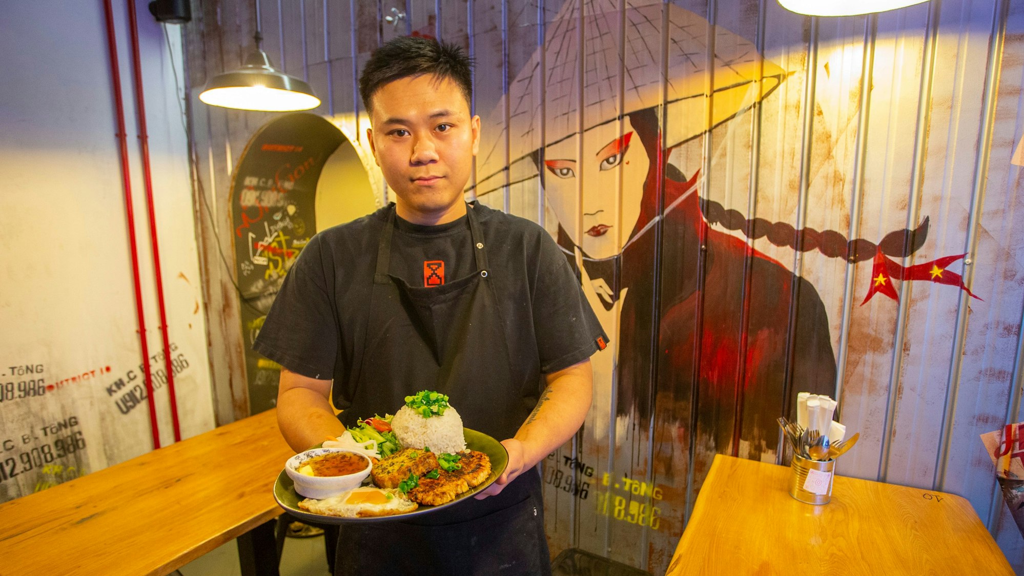 Quan Nguyen steht mit einem vollen Teller in der Hand in seinem Restaurant.