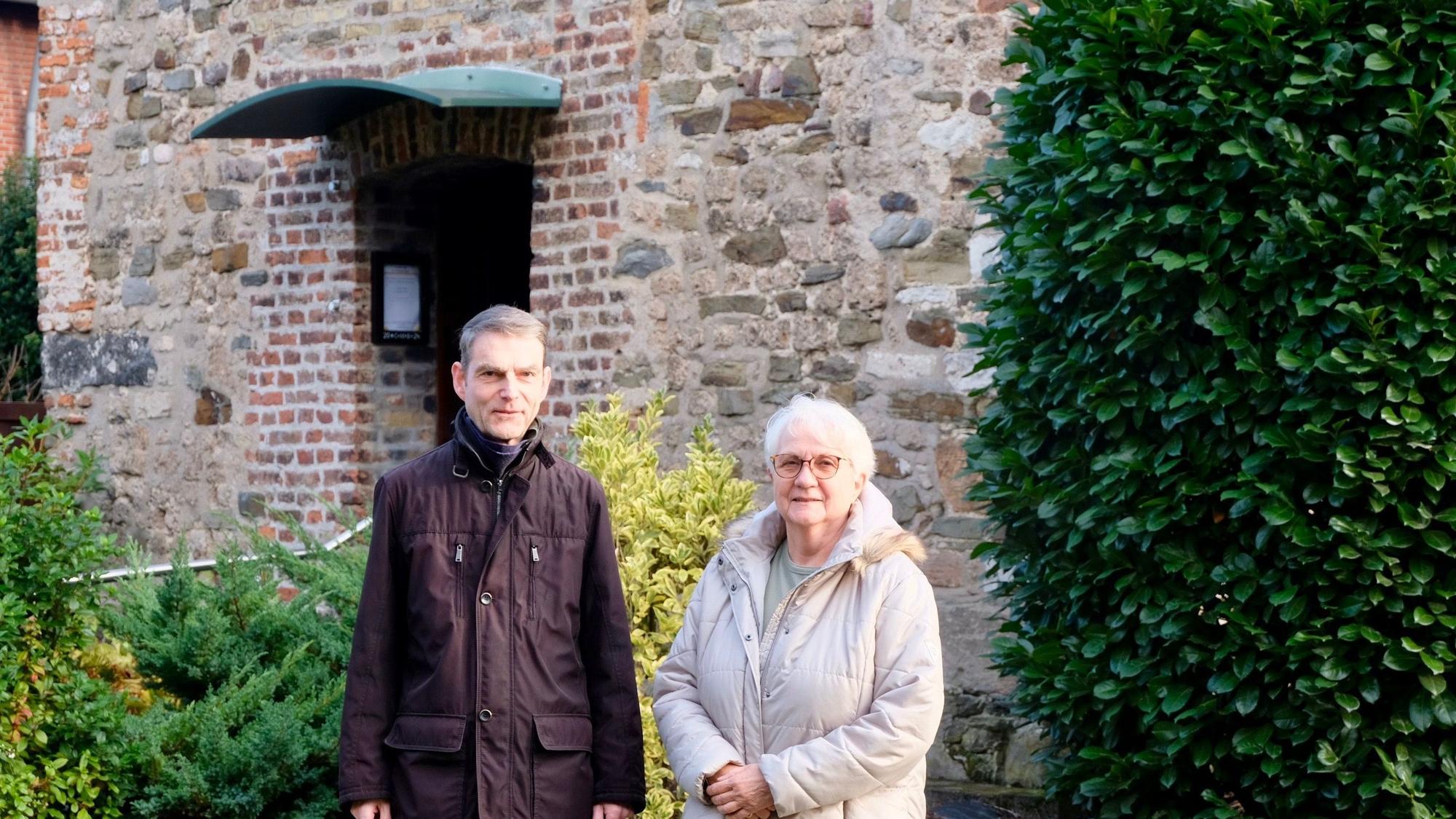 Ein Mann und eine Frau stehen vor einer alt aussehenden Fassade einer Kapelle.