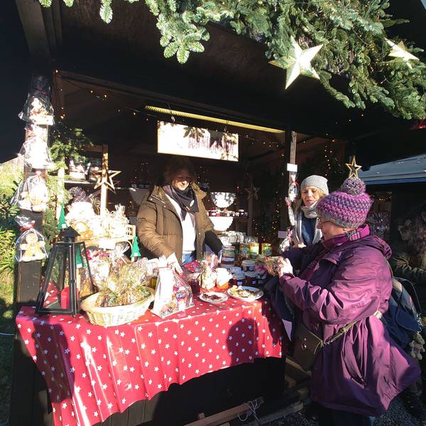 Eine Frau verkauft Gläser an zwei Frauen vor ihrem Stand.