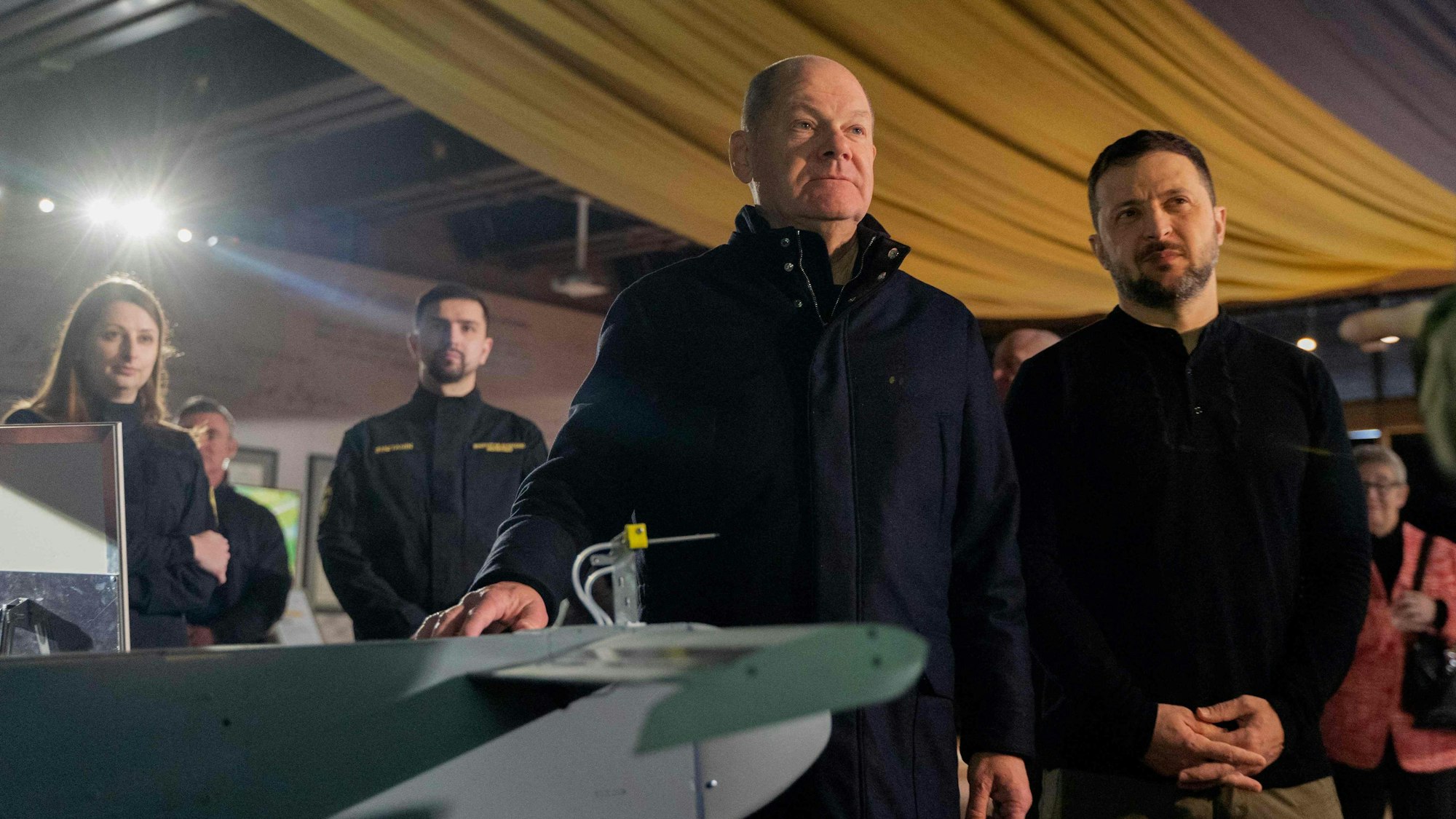 Ukrainian President Volodymyr Zelensky (R) and German Chancellor Olaf Scholz (C) get acquainted with the latest drones during Scholz's visit to Kyiv, on December 2, 2024, amid the Russian invasion of Ukraine. Scholz made a surprise visit to war-torn Ukraine on Monday to reaffirm Berlin's support for Kyiv in its fight against Russia. (Photo by Tetiana DZHAFAROVA / AFP)