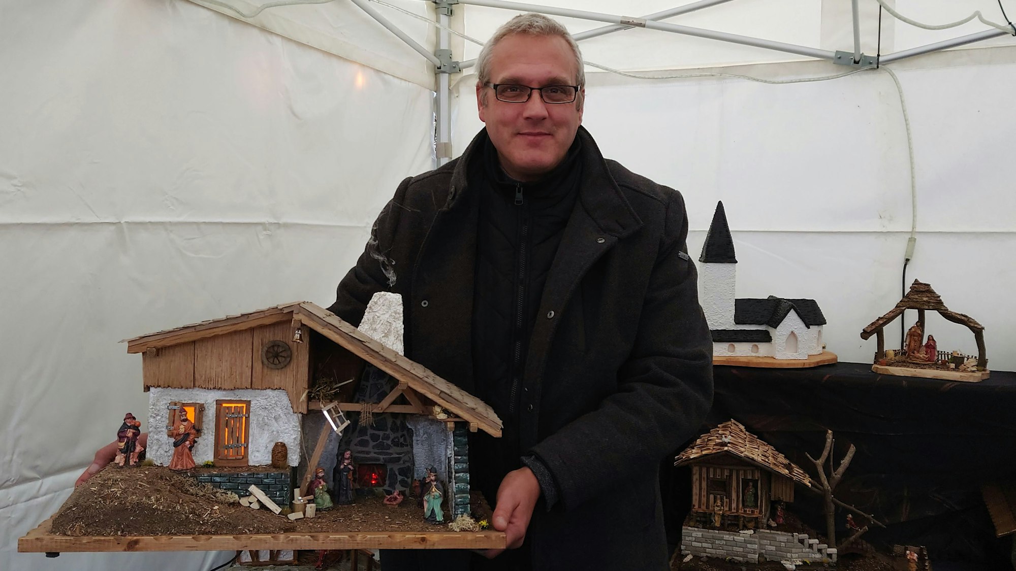 Ein Mann hält eine Weihnachtskrippe in die Kamera.