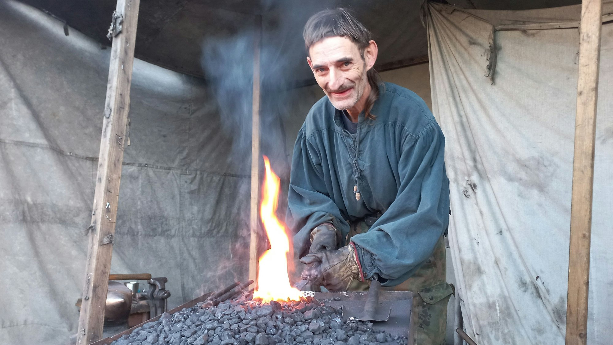 Ein Mann steht vor einem aufflackernden Kohlfeuer.