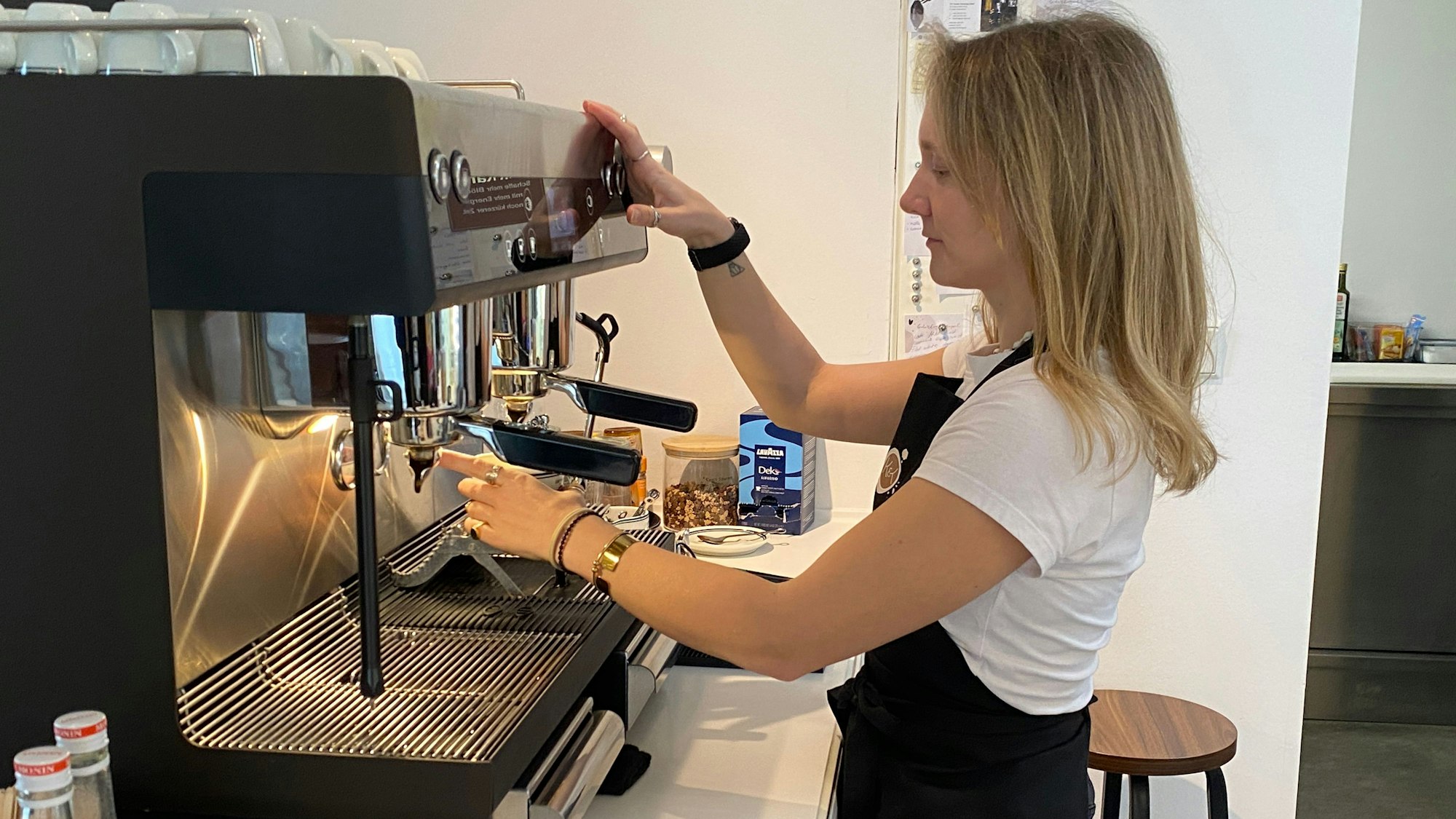 Marie Spiels hält eine Tasse und den Hahn der Maschine.