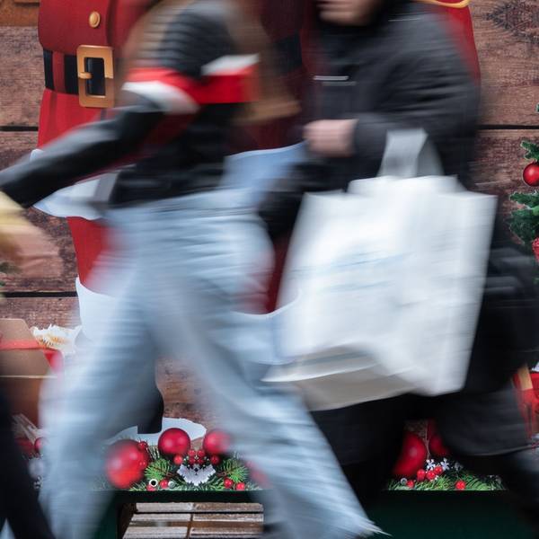 Passanten gehen an einem weihnachtlich geschmückten Verkaufsstand vorbei.