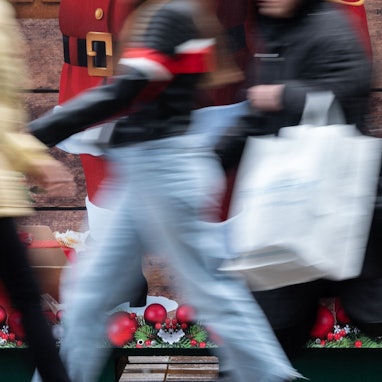 Passanten gehen an einem weihnachtlich geschmückten Verkaufsstand vorbei.