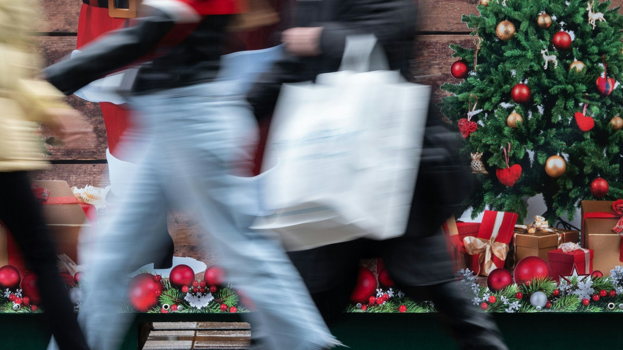 Passanten gehen an einem weihnachtlich geschmückten Verkaufsstand vorbei.