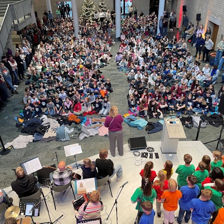 Die Piazetta des Rathauses ist von Kindern gefüllt, die auf dem Boden sitzen und singen.
