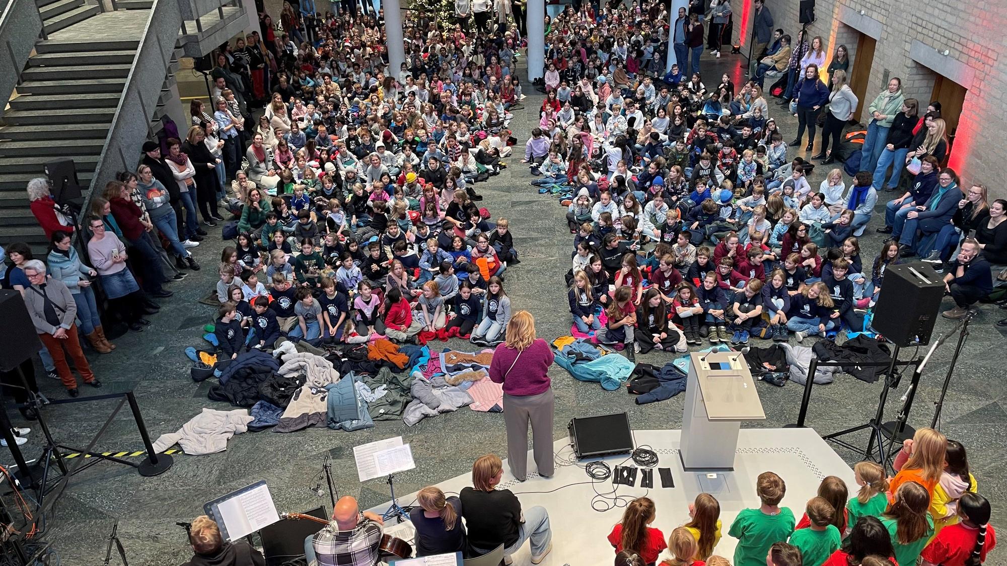 Die Piazetta des Rathauses ist von Kindern gefüllt, die auf dem Boden sitzen und singen.