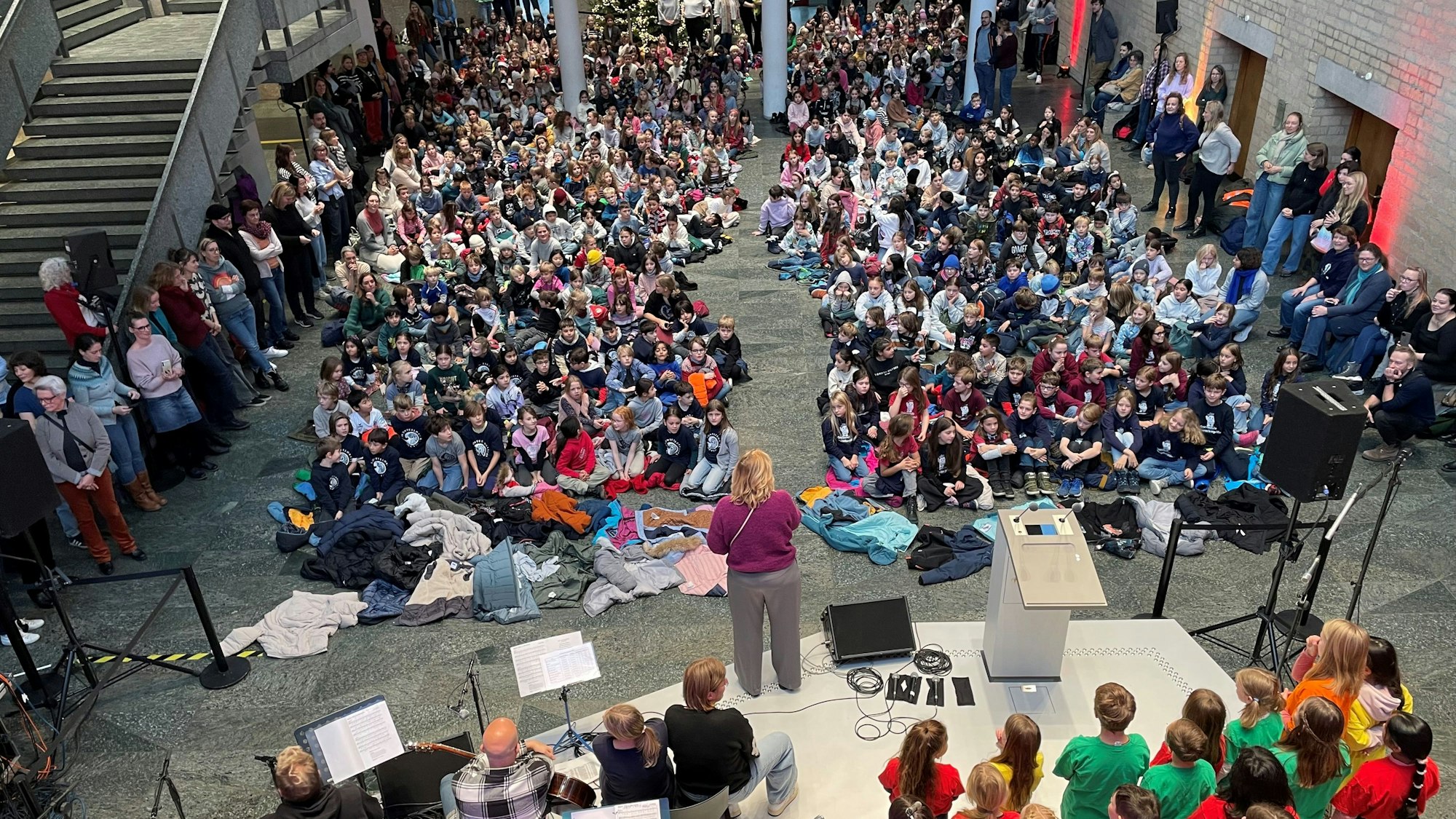 Die Piazetta des Rathauses ist von Kindern gefüllt, die auf dem Boden sitzen und singen.