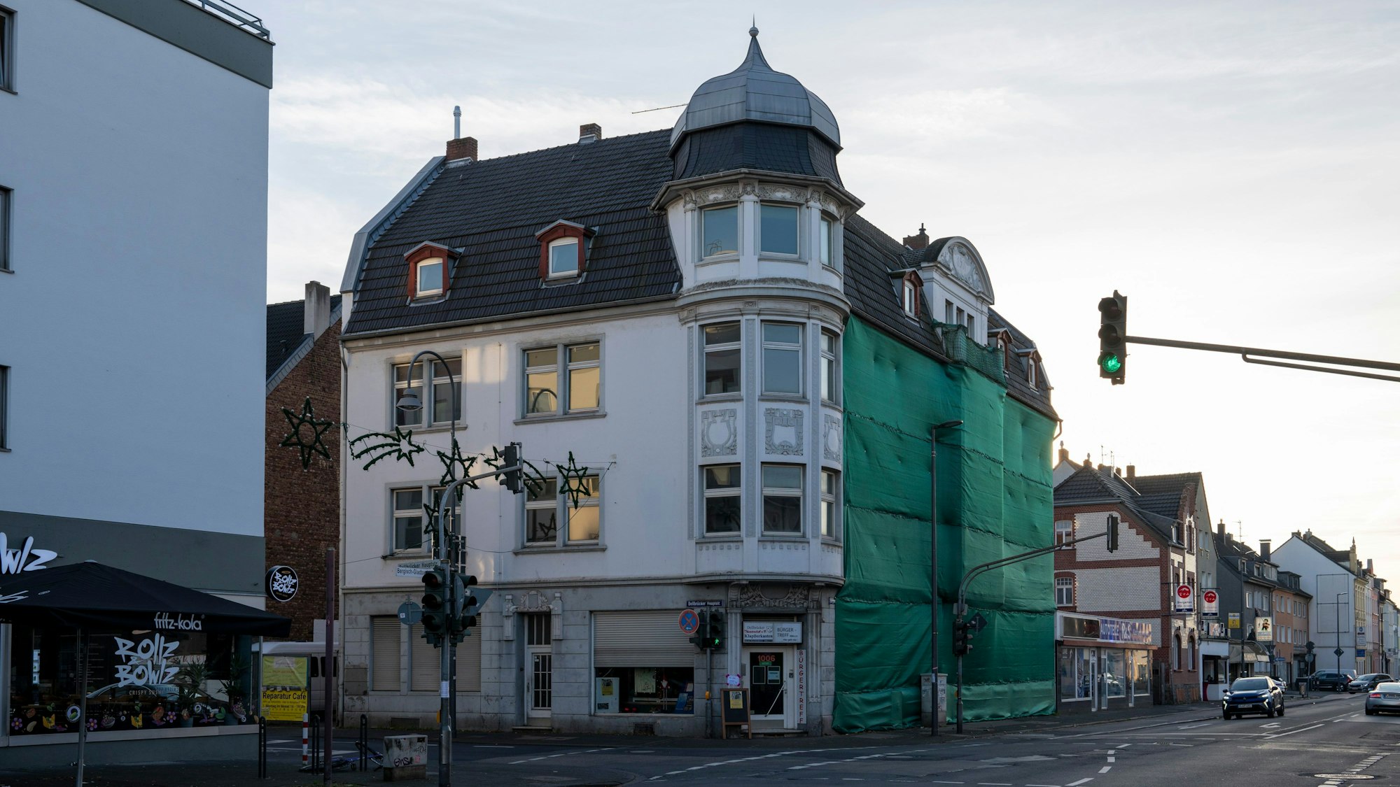 Blick auf ein Eckhaus, dessen Fassade zum Teil verhängt ist.