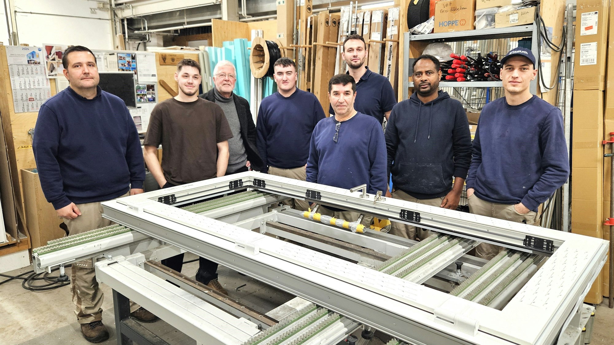 Lehrer Peter Ismar steht in der Werkstatt zwischen den Männern, die er bei der Firma Pfeil in Ripsdorf unterrichtet.