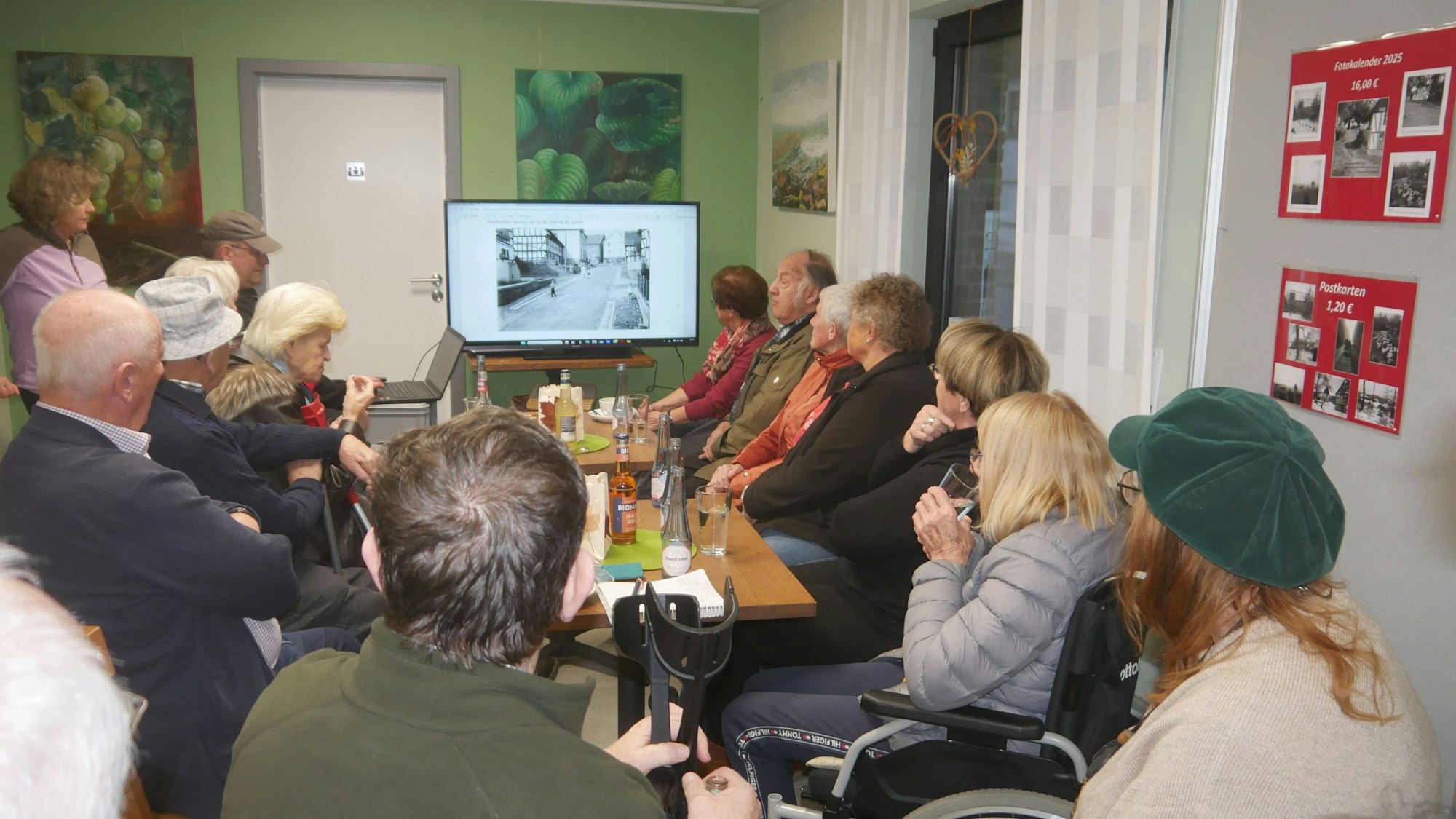Menschen blicken auf einen Bildschirm.